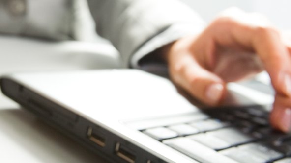 Close-up of hands typing on a laptop keyboard.